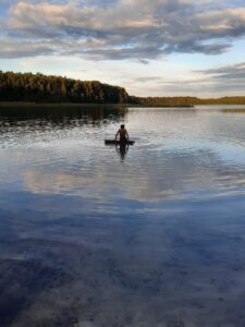 Osoba pływająca na materacu po czystym jeziorze